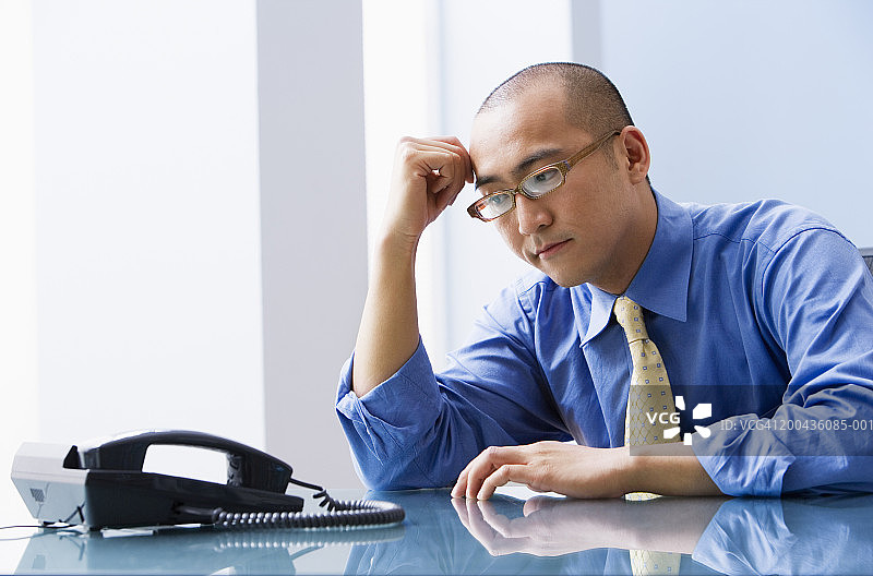年轻商人看着办公桌上的手机图片素材