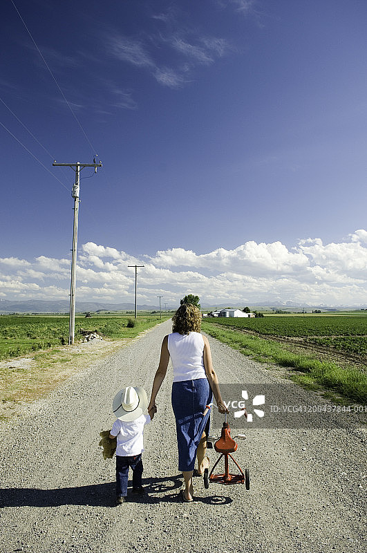 母亲和男宝宝（21-24个月）在路上骑三轮车（后视图）图片素材
