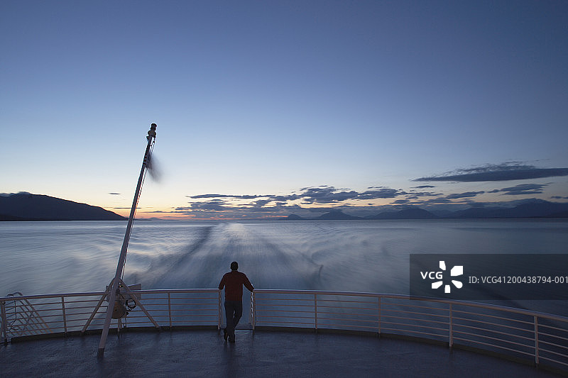 美国阿拉斯加州男子站在渡轮船尾看日落，后视图图片素材