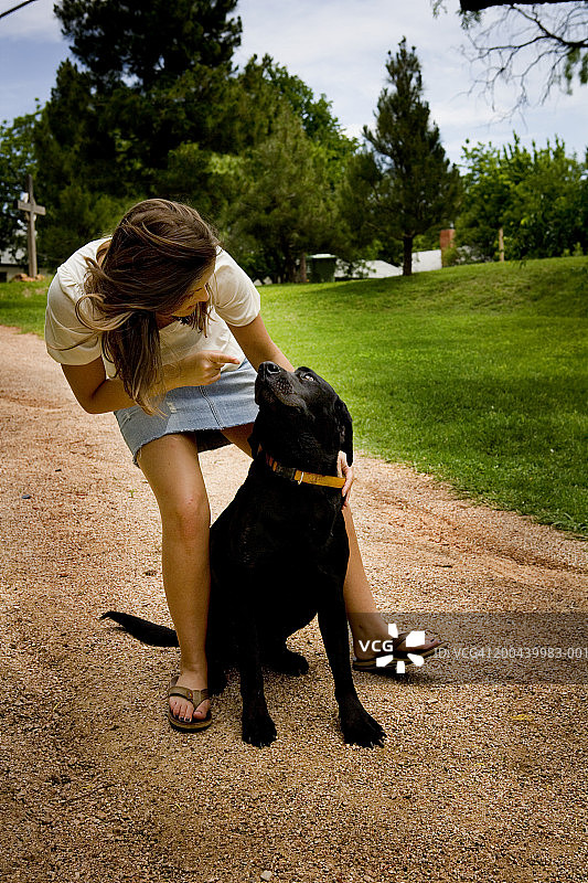 年轻女子在户外抱着黑色拉布拉多犬图片素材