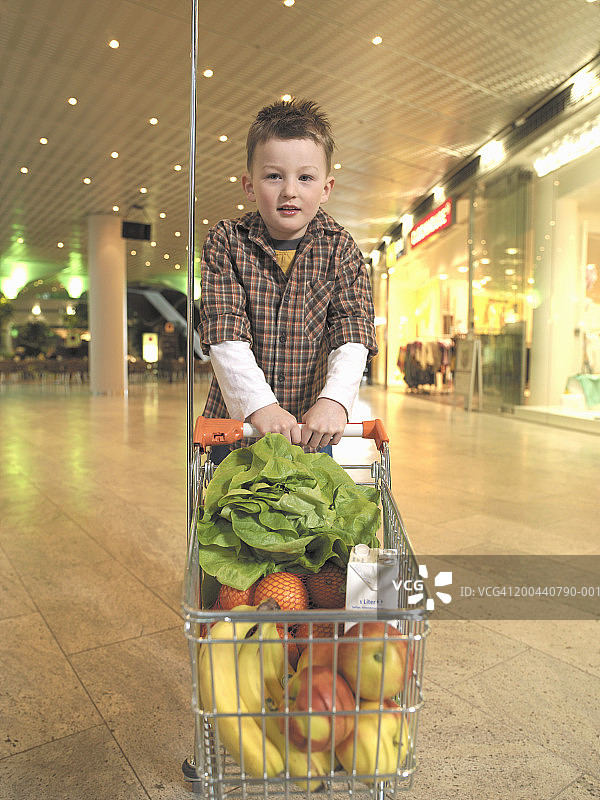 男孩（5-7岁）抱着装满水果和蔬菜的手推车图片素材
