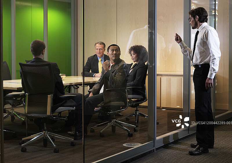 商务会议中的高管，男子敲玻璃打断会议图片素材