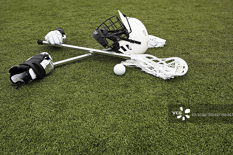人造草皮上的长曲棍球棒、手套、球和运动头盔图片素材