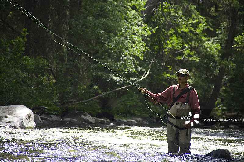 穿着涉水裤在河里飞蝇钓鱼的男人（50-55岁）图片素材