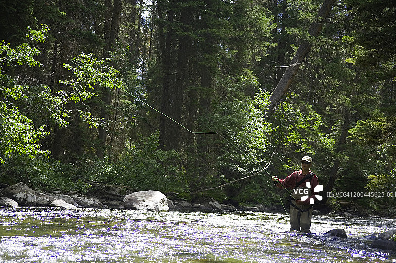 穿着涉水裤在河里飞蝇钓鱼的男人（50-55岁）；日落图片素材