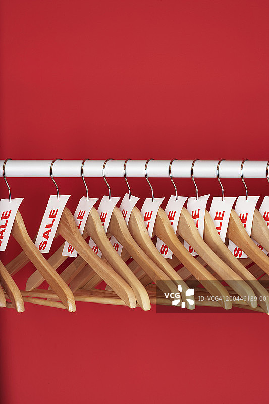 红色背景上的挂满促销标签的衣架图片素材