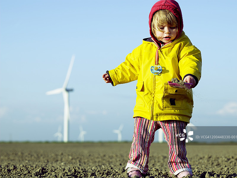小女孩在风力发电场玩沙子（低角度）图片素材