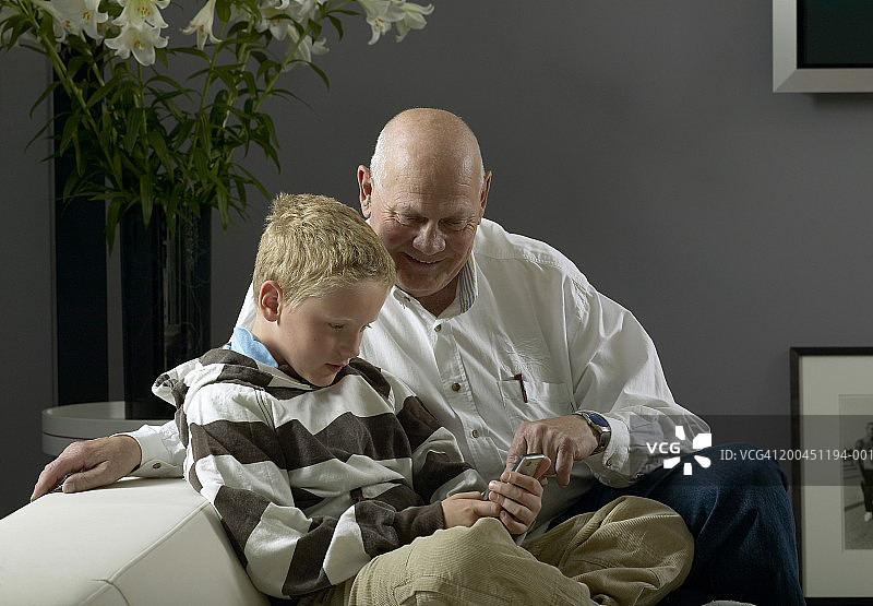 年长的男人和男孩(8-10岁)使用手机图片素材