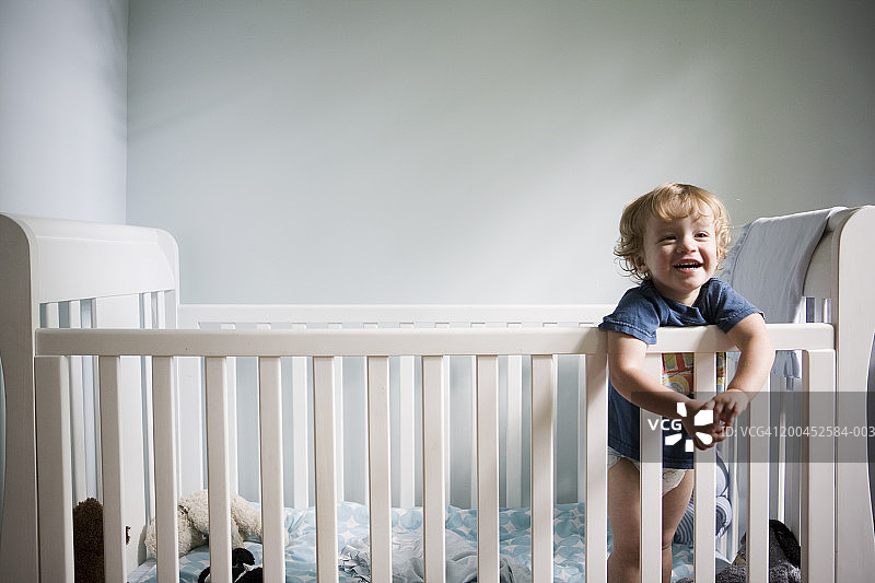 幼儿男孩（21-24个月）在婴儿床里微笑，特写图片素材