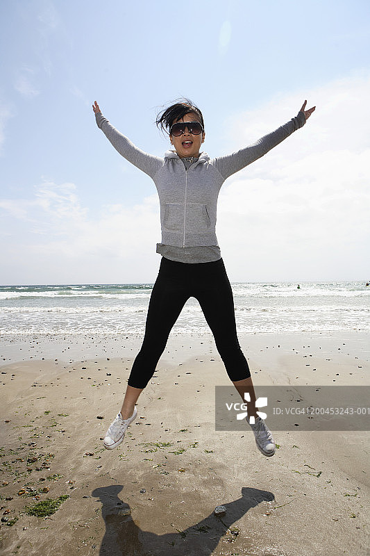年轻女子在海滩上蹦蹦跳跳图片素材