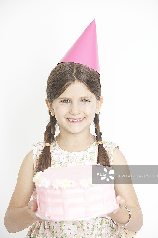 戴着派对帽，拿着蛋糕的女孩（6-8岁）肖像图片素材