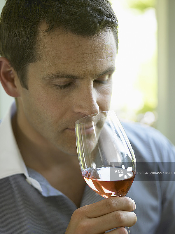 男人近距离闻葡萄酒杯中的酒图片素材