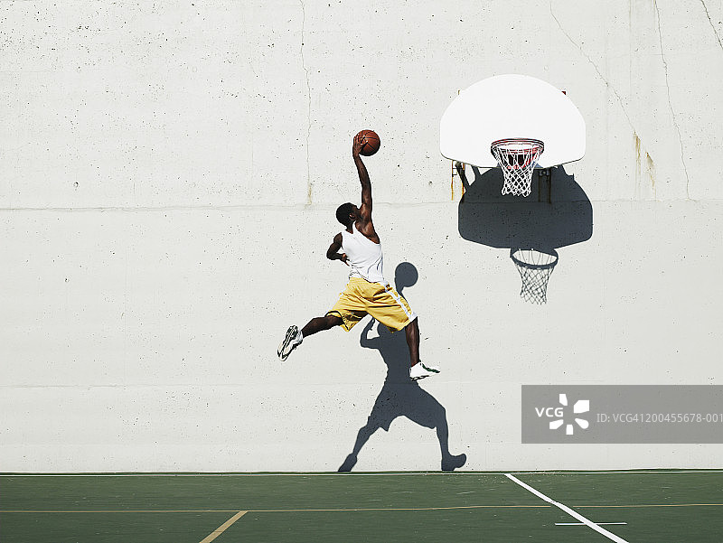 年轻男子在室外球场投篮，侧视图图片素材