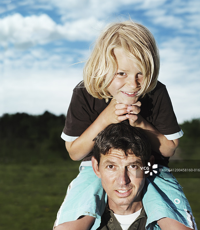 8-10岁男孩坐在父亲肩上肖像特写图片素材