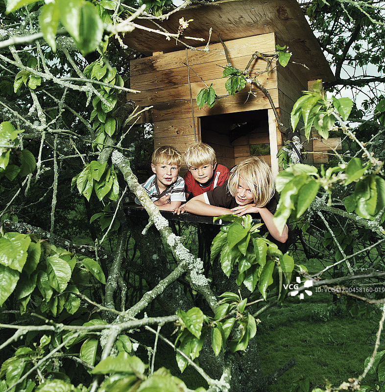 躺在树屋入口处的三个兄弟（4-9岁），肖像图片素材