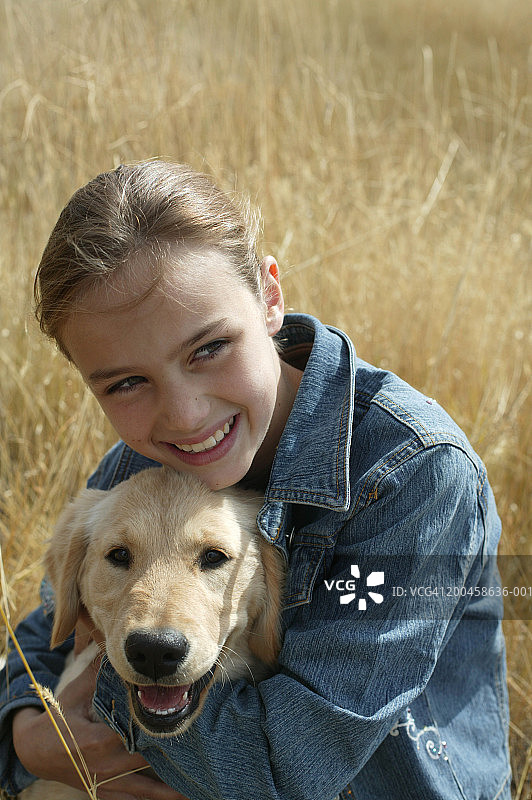 女孩（9-11岁）在田野里拥抱黄色拉布拉多寻回犬幼犬图片素材