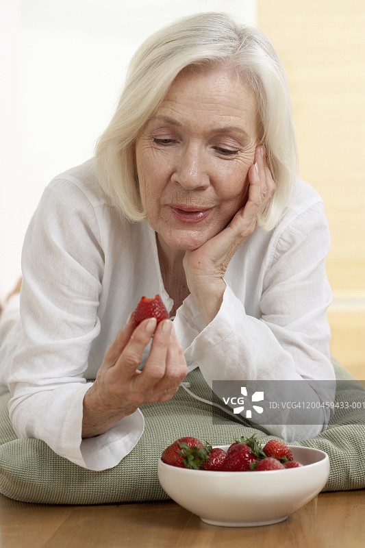年长的女人看着草莓图片素材