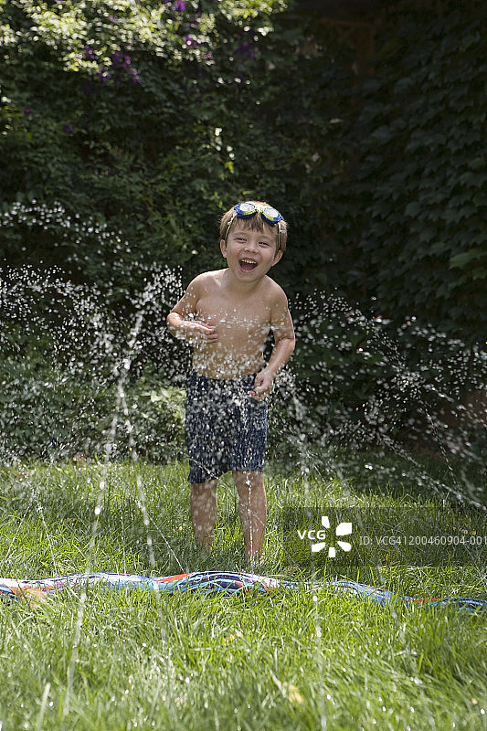 在花园洒水器下玩耍的男孩（3-5岁）图片素材