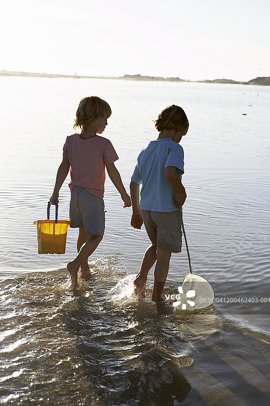 两个男孩（5-7岁）在泻湖里拿着渔网和水桶图片素材