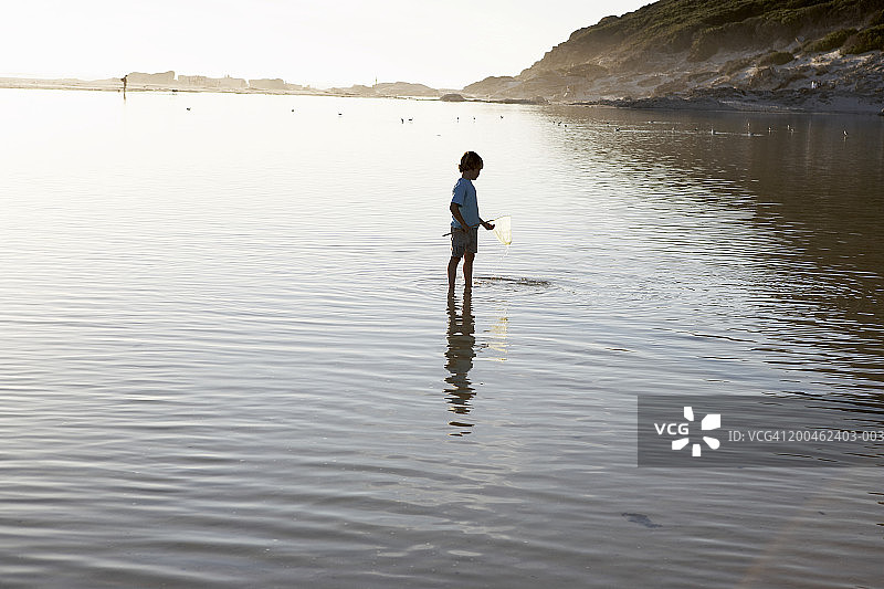 站在泻湖里，手持渔网的男孩（5-7岁）图片素材