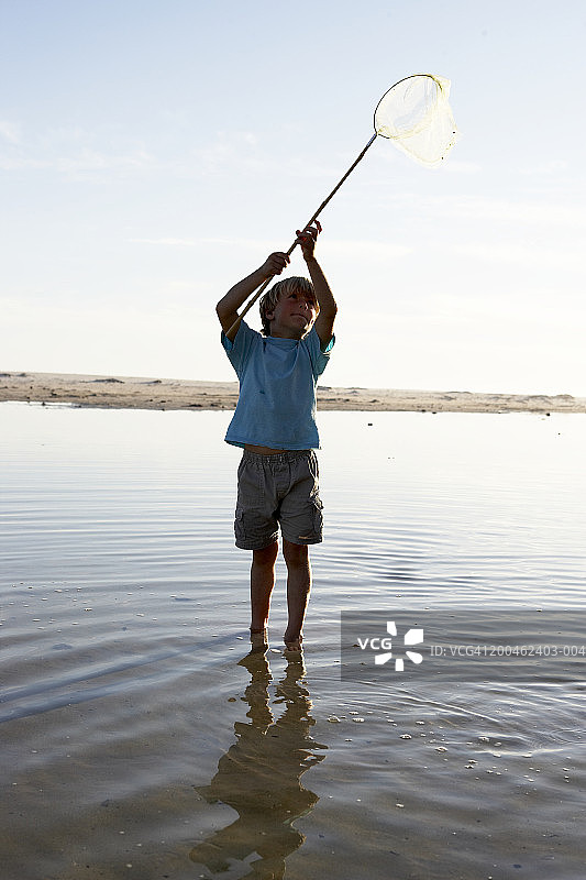 在泻湖中举着渔网的男孩图片素材