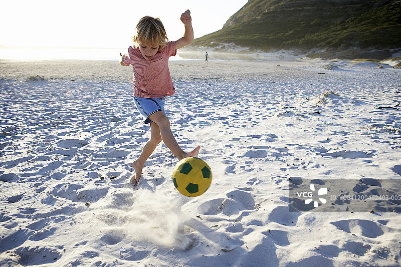 男孩（4-6岁）在沙滩上踢足球图片素材