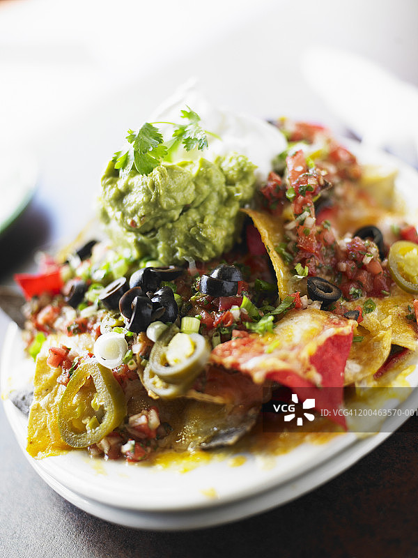 搭配鳄梨酱、萨尔萨酱、橄榄、酸奶油和墨西哥辣椒的玉米片图片素材