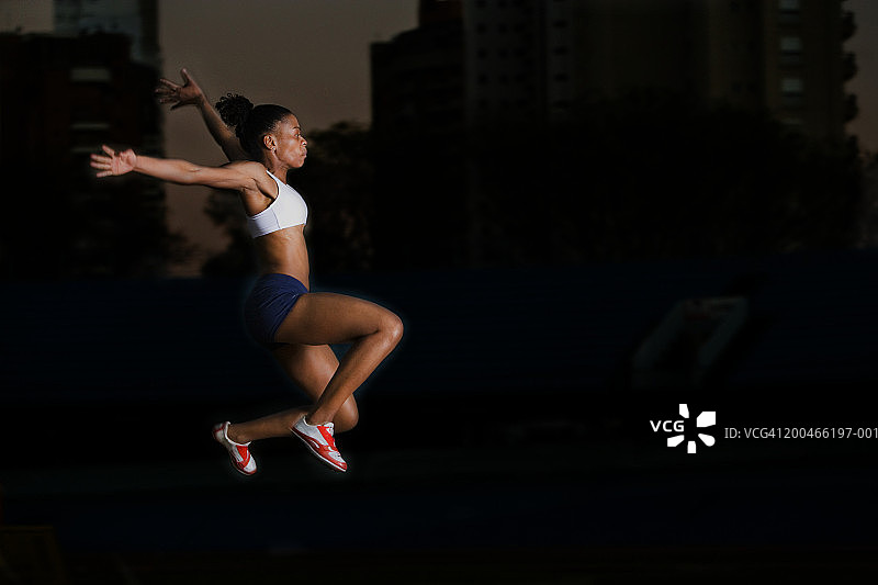 夜间侧视跳远女运动员图片素材