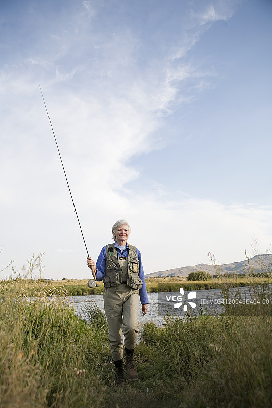 站在河边，手持飞蝇钓装备的年长女人肖像图片素材
