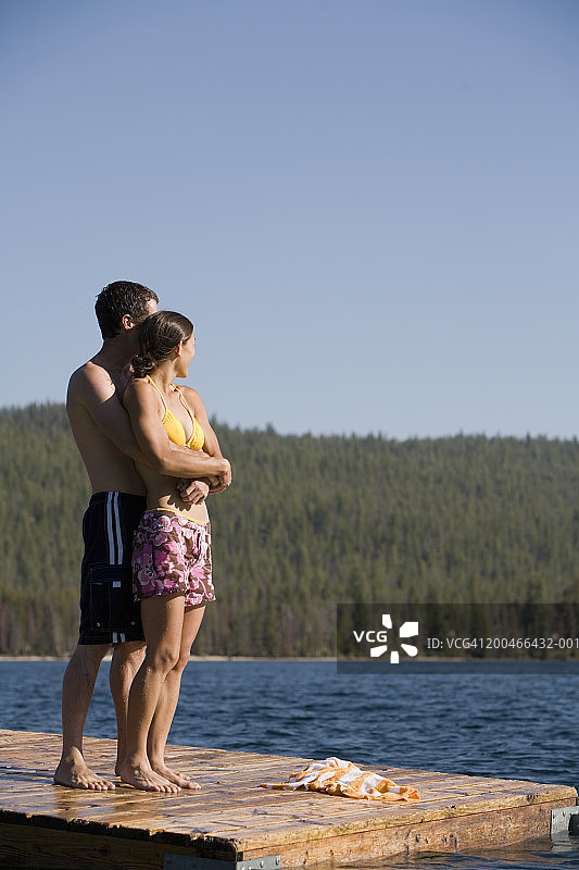 年轻男人和女人在码头上拥抱的侧面照图片素材