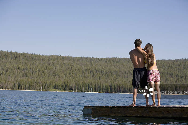 年轻女子靠在码头上年轻男人的肩膀上，后视图图片素材