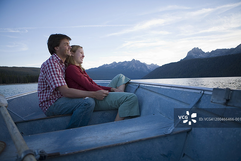 年轻男人和女人在黄昏时分于湖上划船拥抱（侧视图）图片素材