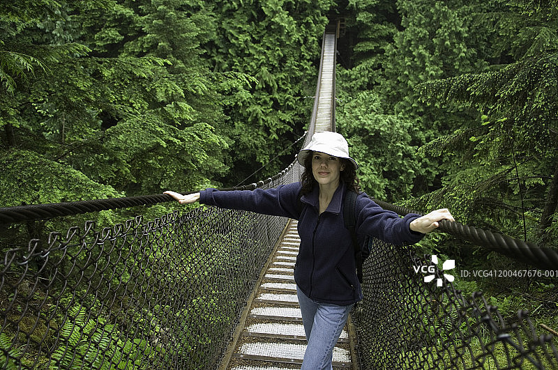 女子站在森林悬索桥上，肖像图片素材