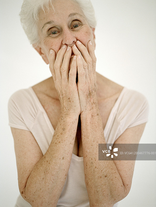 年长妇女用手捂着嘴，肖像图片素材