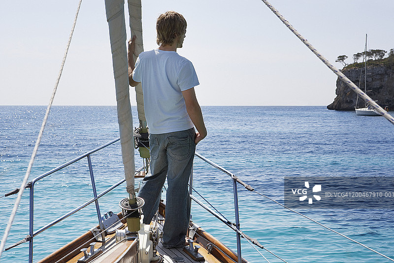 年轻男人站在帆船前，后视图图片素材