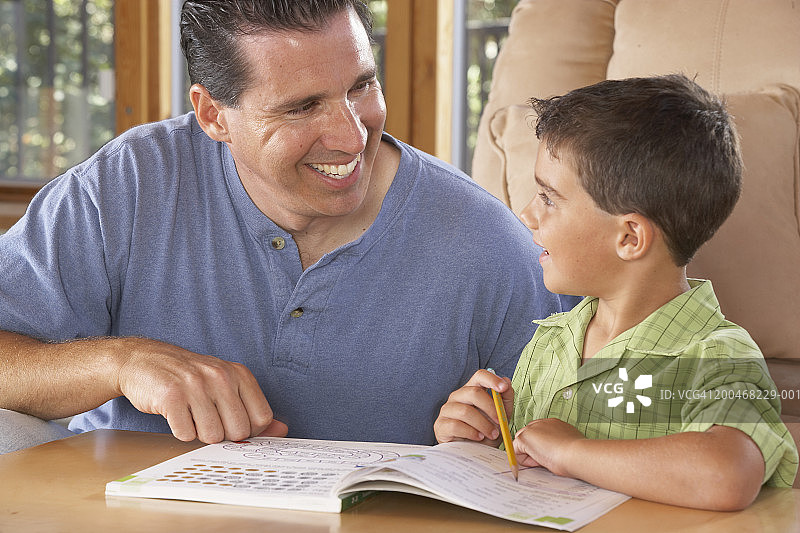 父亲笑着帮助儿子（5-7岁）做作业图片素材
