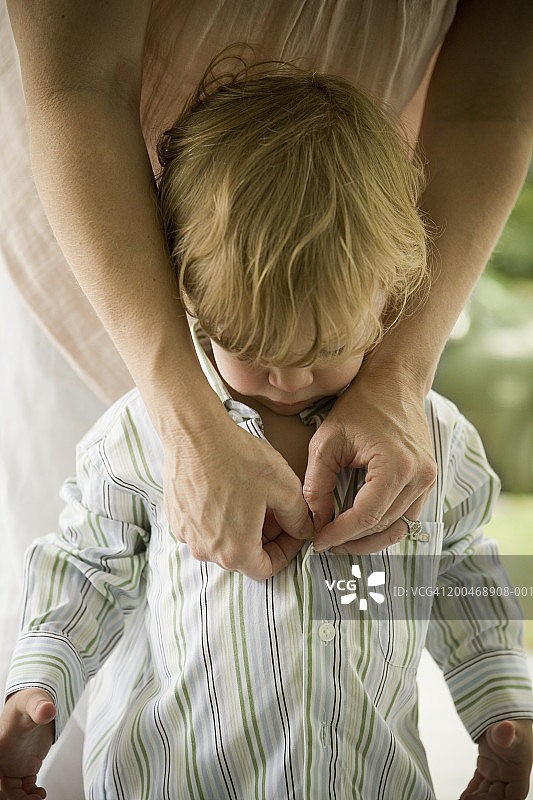母亲给男童（21-24个月）扣衬衫扣子图片素材