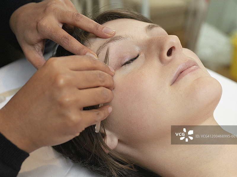 年轻女人拔眉毛特写图片素材