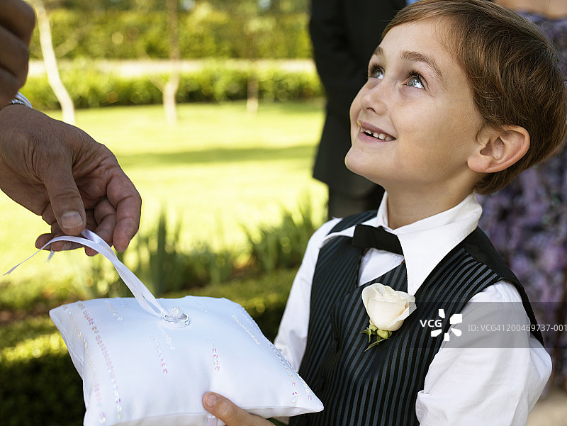 男花童（6-7岁）抬头看着新郎拿起结婚戒指图片素材