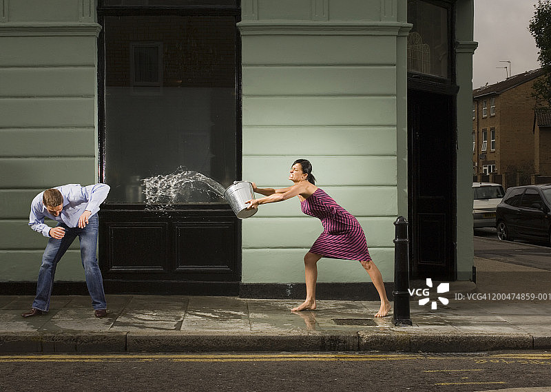 年轻女人在户外用水桶泼男人图片素材