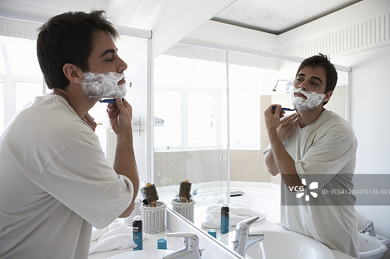 男人在浴室镜中刮脸，侧面视角图片素材