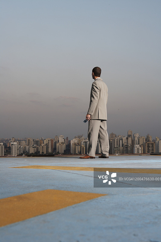 年轻商人于屋顶远眺城市景观（背影）图片素材