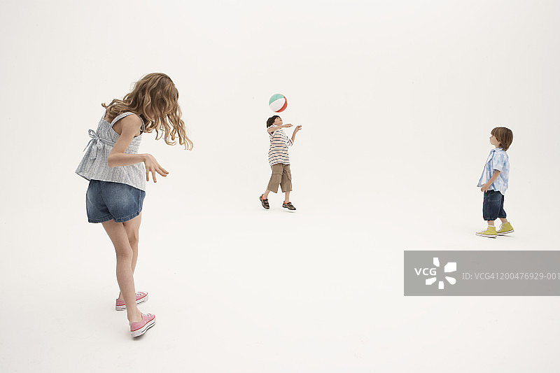 三个孩子（7-11岁）在玩沙滩球图片素材