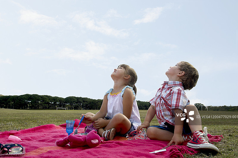 兄妹（3-5岁）坐在公园地毯上，仰望天空图片素材