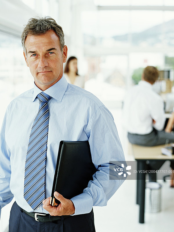 中年商人手持文件站在办公室图片素材