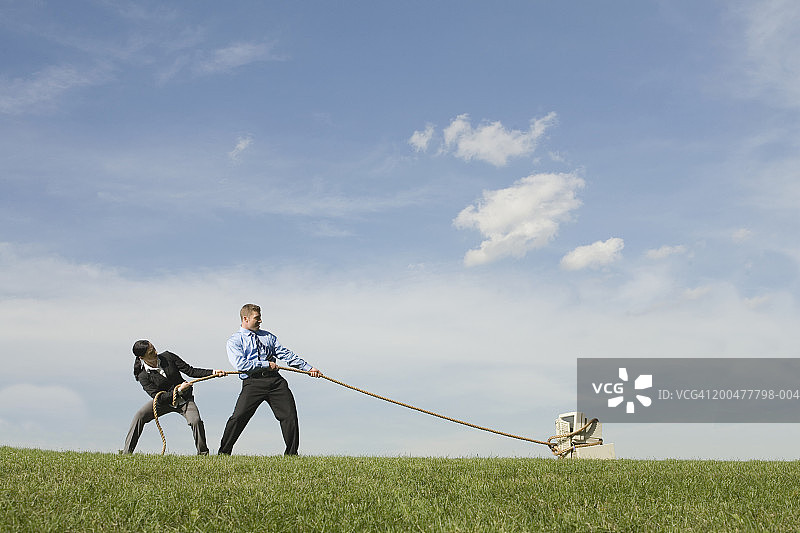 商人们用绳子拉着旧电脑穿过田野，侧视图图片素材