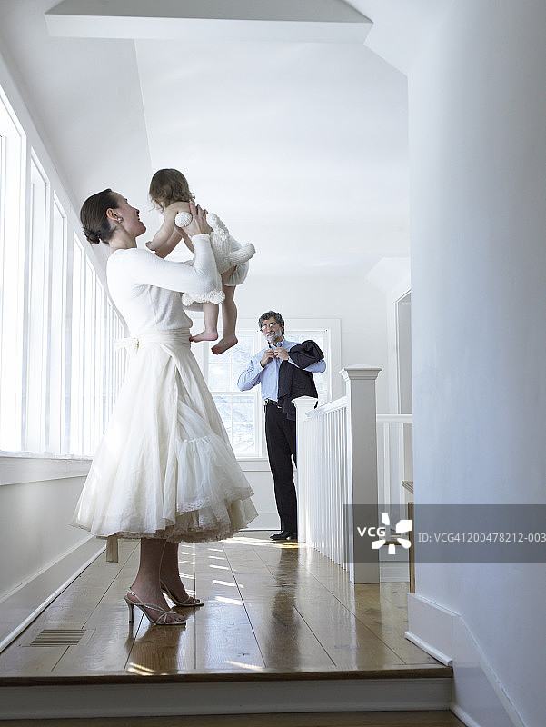 母亲抱起女童（18-21个月大），看着父亲图片素材