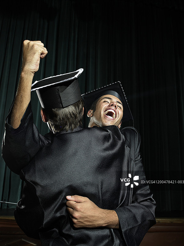 男人们拥抱，一个举起拳头庆祝图片素材