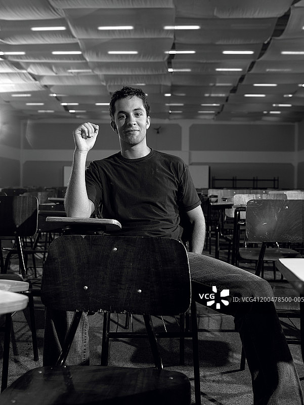 学生坐在桌旁微笑，黑白肖像图片素材