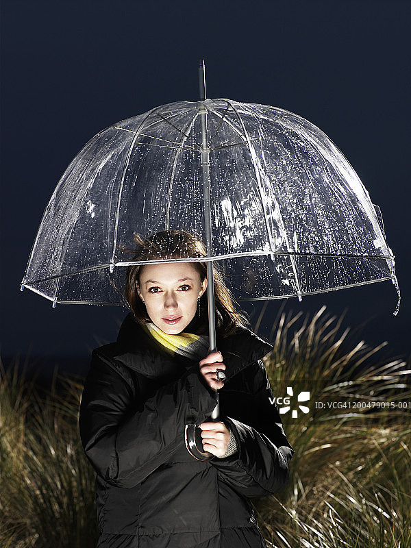 黄昏时分户外持伞的年轻女子肖像图片素材